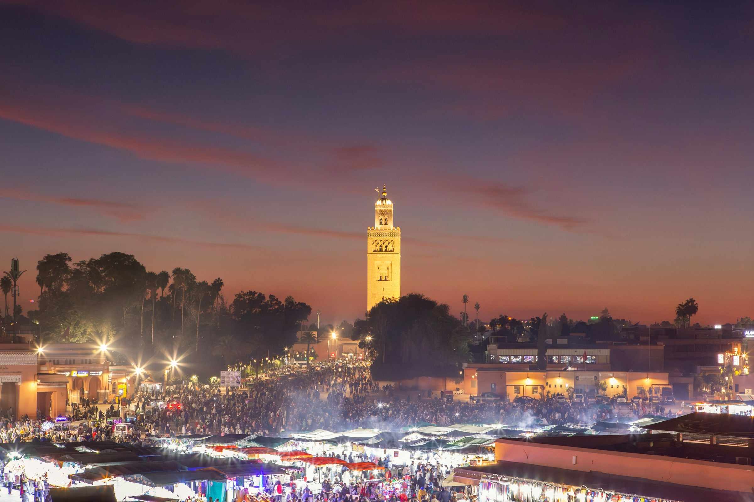 Jemaa el-Fnaa square in Marrakech at dusk, with the Koutoubia minaret lit up